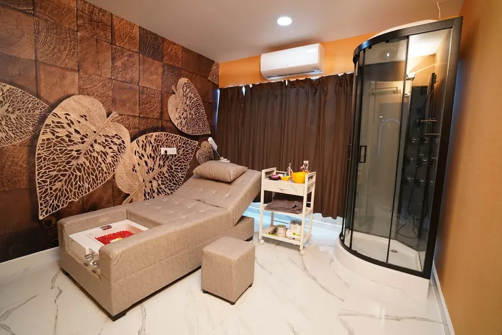 A body care room with a lounger, a foot basin and a steam shower at Hiwaga Vijayawada